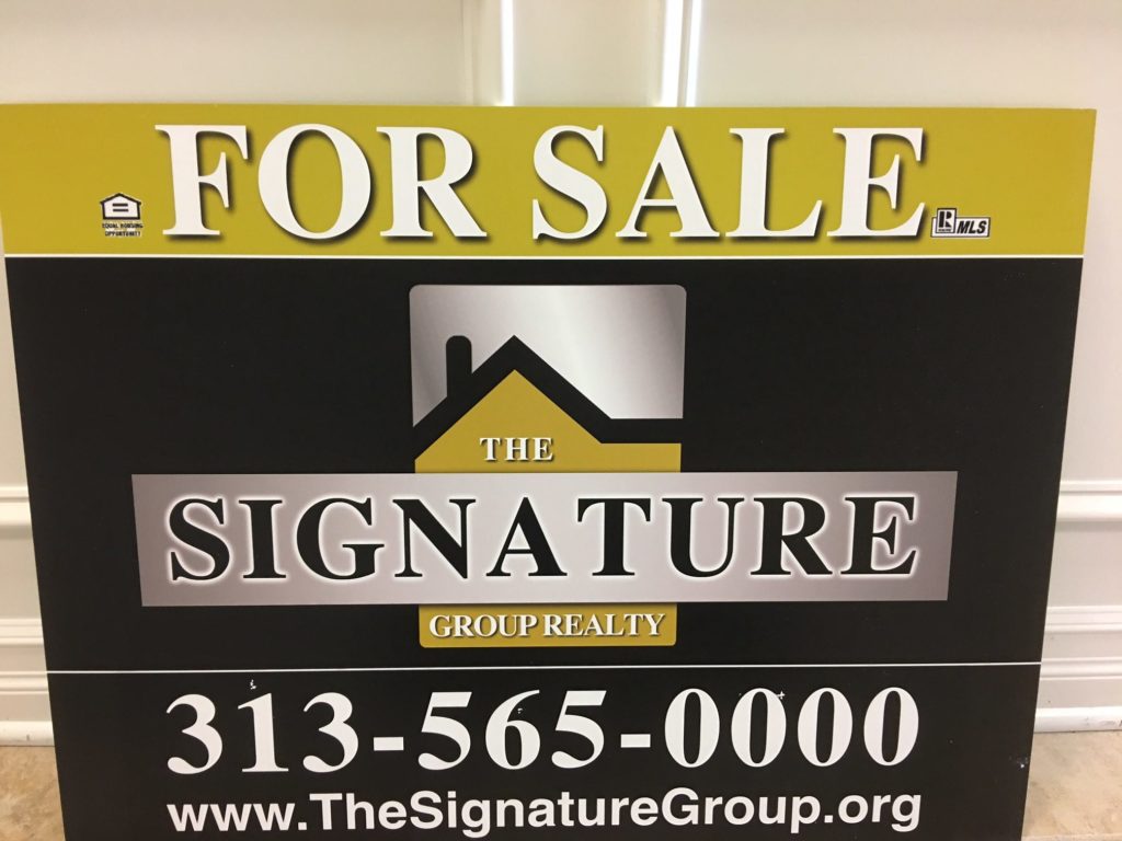 Real estate sign for The Signature Group with contact information.
