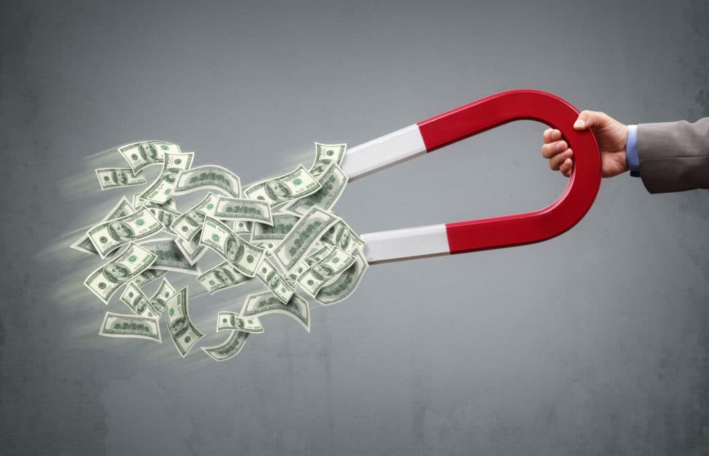 A horseshoe magnet attracting dollar bills.