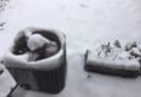 Outdoor HVAC unit covered in snow on a snowy day.