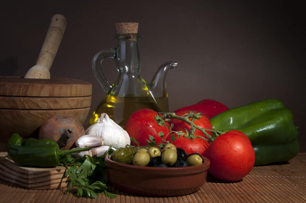 A rustic arrangement of tomatoes, olives, garlic, and olive oil.