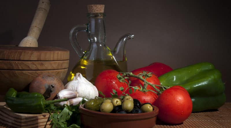 A rustic arrangement of tomatoes, olives, garlic, and olive oil.