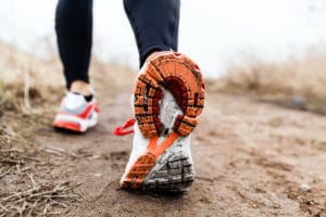 Close-up of a runner's shoe with mud on the sole during a trail run.