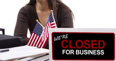 Sign showing business closed with American flags in the background.