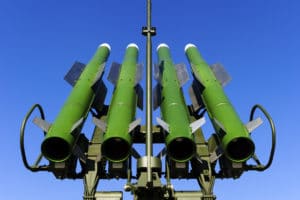 A close-up of green military missiles against a clear blue sky.