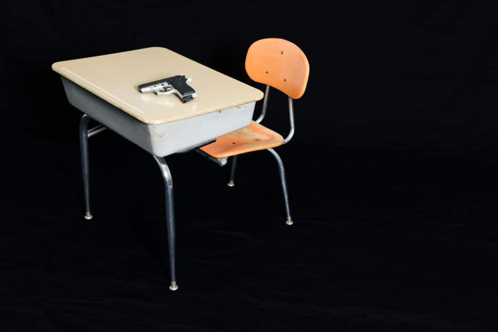 Vintage school desk and chair with wooden seat and metal frame against black background.