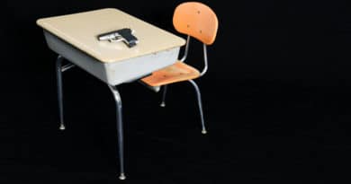 Vintage school desk and chair with wooden seat and metal frame against black background.