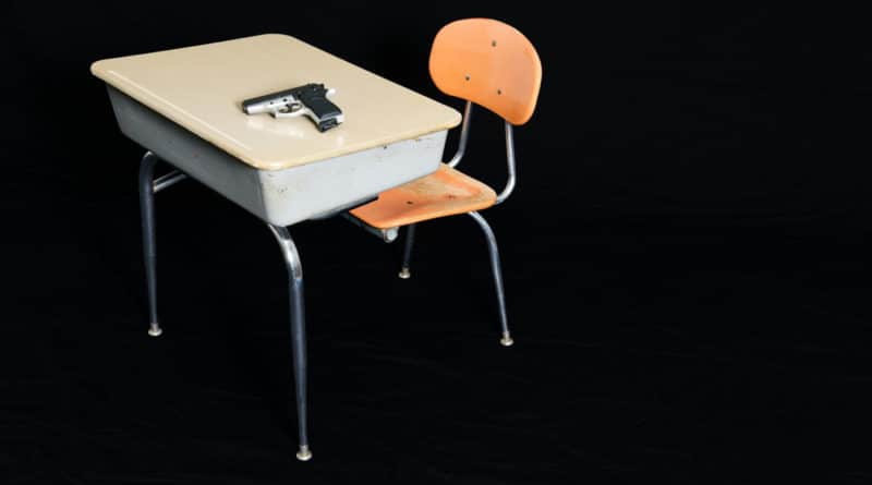 Vintage school desk and chair with wooden seat and metal frame against black background.