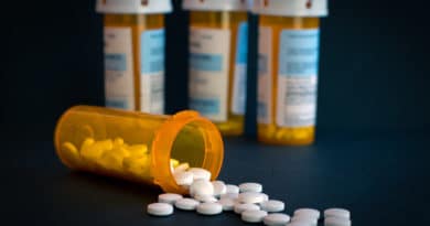 Spilled prescription pills with medicine bottles in the background.