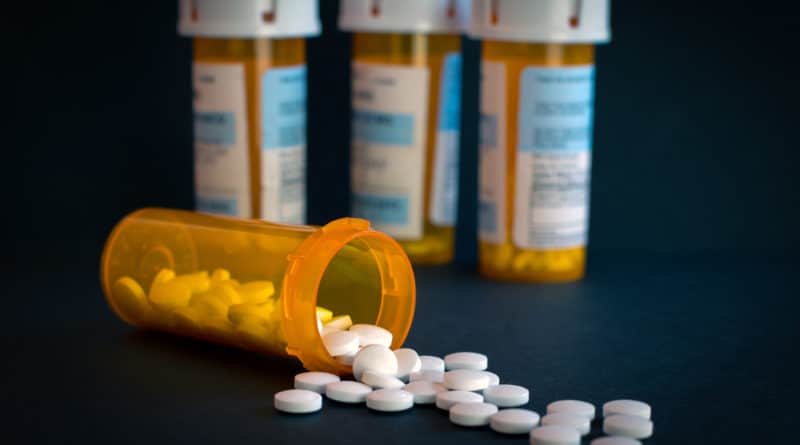 Spilled prescription pills with medicine bottles in the background.