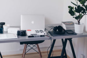 Minimalist workspace with laptop, headphones, and camera on a desk.