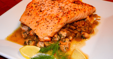 Grilled salmon fillet served on a bed of lentils with lemon wedges and dill garnish.
