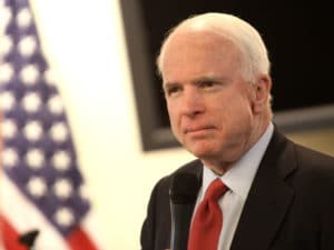 A man speaking at a podium with an American flag in the background.