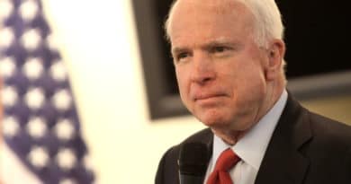 A man speaking at a podium with an American flag in the background.