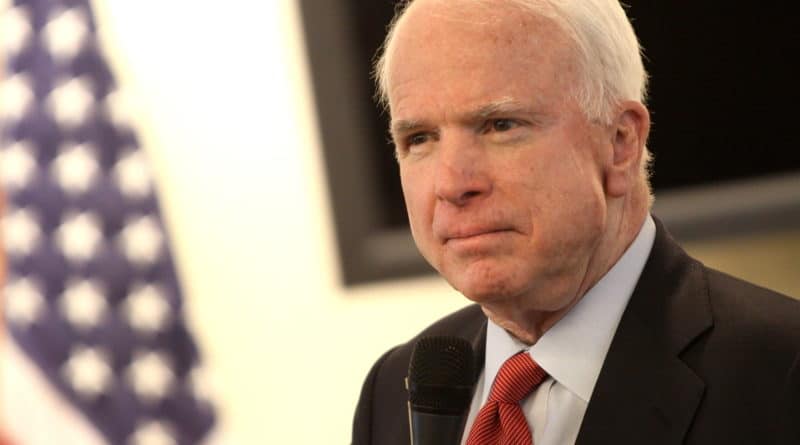 A man speaking at a podium with an American flag in the background.