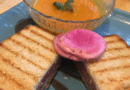 Grilled sandwich with creamy tomato soup and a slice of radish.