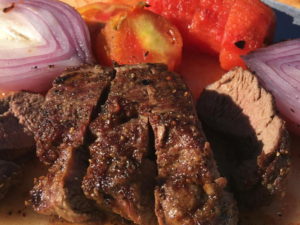 Close-up of a grilled steak with roasted vegetables.