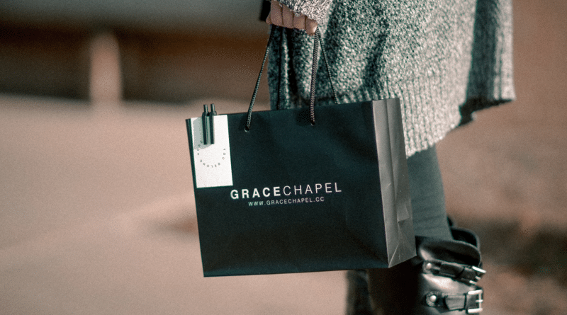 Person holding a Grace Chapel paper bag and a water bottle.