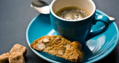 Cup of coffee with biscotti on a blue saucer.