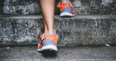 Person wearing orange and gray shoes walking up concrete stairs.