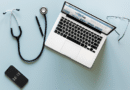 A stethoscope and laptop on a desk, symbolizing digital healthcare.