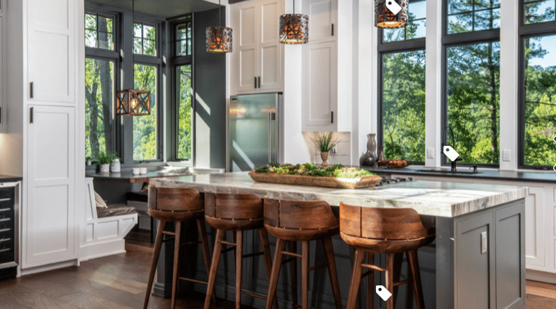 Modern kitchen with wooden stools and pendant lights.