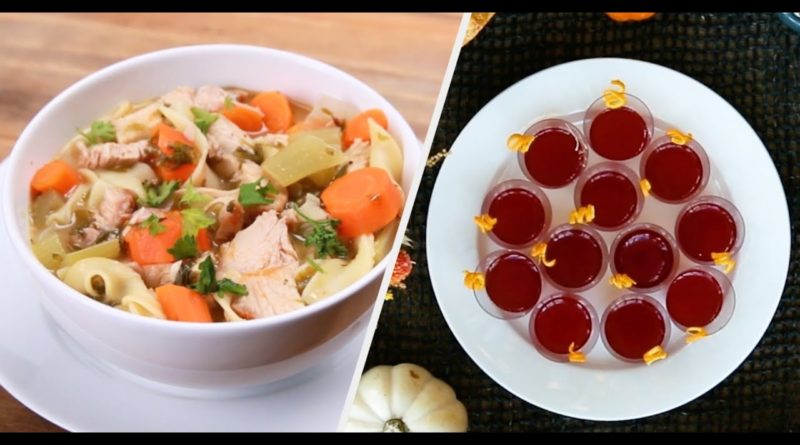 A bowl of chicken soup and a plate of jelly shots on a table.
