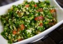 Fresh tabbouleh salad with parsley, tomatoes, and bulgur in a white bowl.