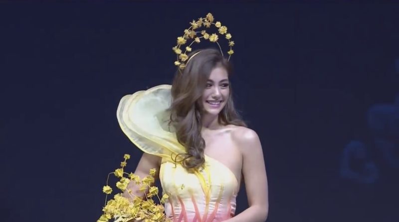 Woman wearing a yellow floral crown and a strapless pastel dress.