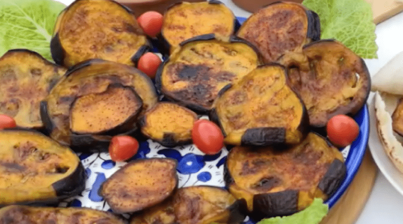 A plate of grilled eggplant slices garnished with lettuce and cherry tomatoes.