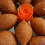 Golden brown kibbeh with a decorative carrot rose in the center.