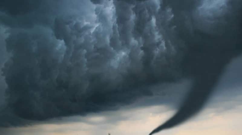 A tornado funnel cloud under dark, stormy skies.