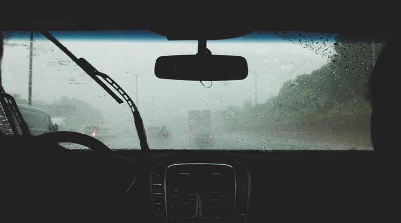 View from inside a car during heavy rain with windshield wipers active.