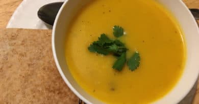 A bowl of creamy pumpkin soup garnished with cilantro, served with toasted bread.