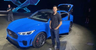 Man standing beside a blue sports car at an event.