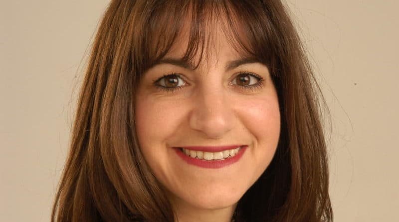 Portrait of a smiling woman with brown hair and bangs.