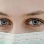 Close-up of blue eyes above a surgical mask.