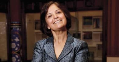 Smiling woman in a gray blazer with a confident pose.