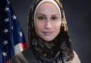 Professional woman wearing a hijab with an American flag background.
