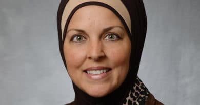 Portrait of a smiling woman wearing a hijab and leopard print scarf.
