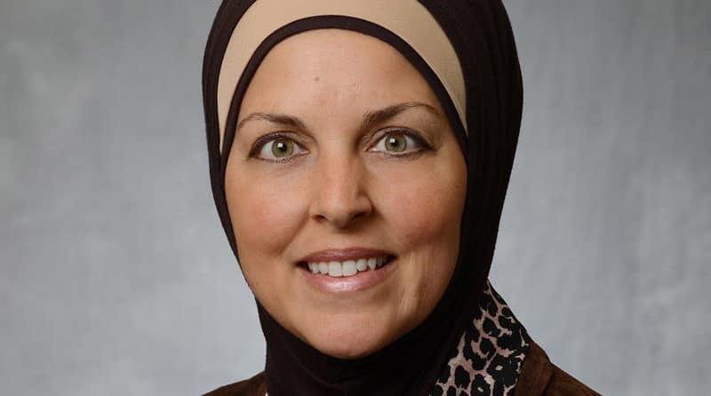Portrait of a smiling woman wearing a hijab and leopard print scarf.