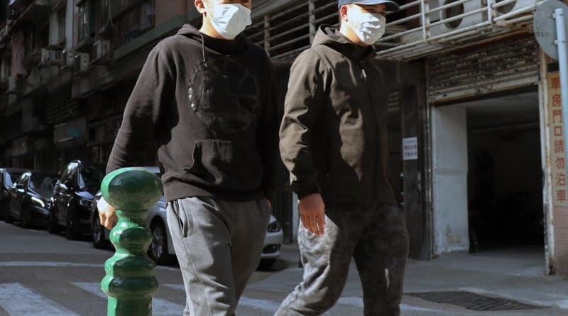 Two men wearing face masks walking outdoors in casual attire.