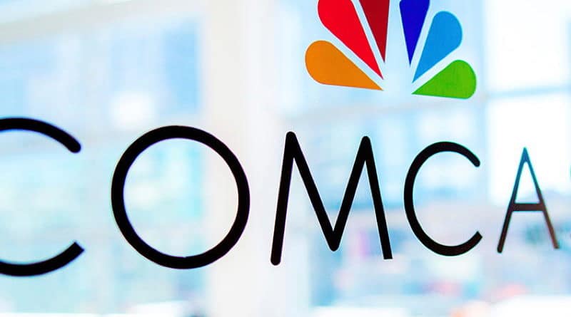 Comcast logo on glass window with a blurred office background.