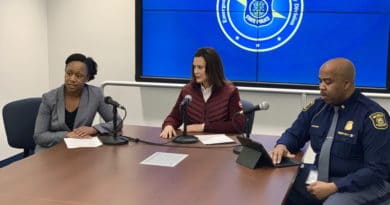 Three professionals in a meeting room with a presentation screen.