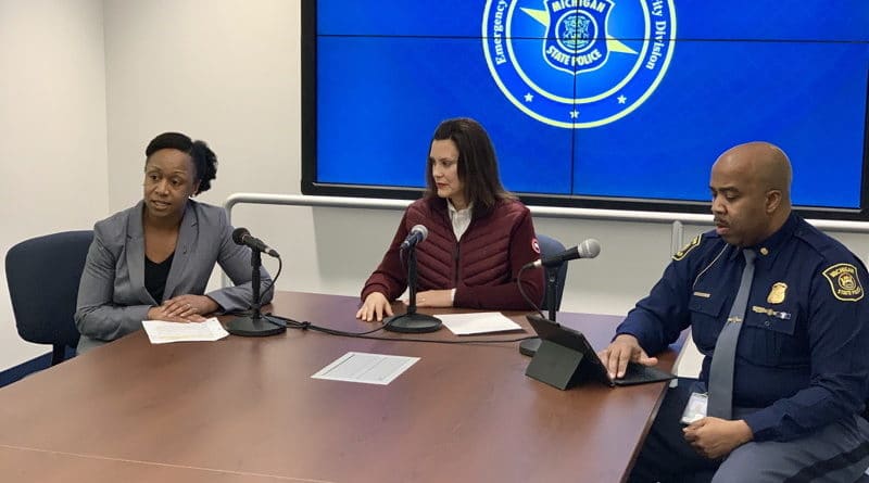 Three professionals in a meeting room with a presentation screen.