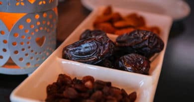 Three sections of dried fruits including prunes and raisins on a white dish.