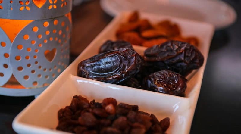 Three sections of dried fruits including prunes and raisins on a white dish.