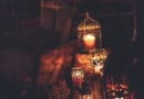 Warm candlelight glowing inside ornate lanterns in a dim setting.