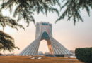 Azadi Tower framed by trees at sunset.