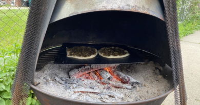 Two pizzas baking inside a wood-fired oven with glowing embers.