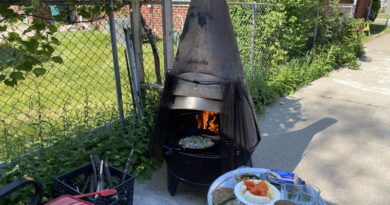 Outdoor chiminea grilling with food on a nearby table.